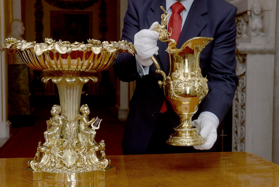 Позолоченный серебряный кувшин почти на 100 лет старше «Купели с лилиями» – его изготовили в 1735 году к крещению короля Георга III. Ручка кувшина украшена фигуркой Геракла, держащего в руках дубину и убивающего гидру, что символизирует торжество христианской добродетели над пороком.