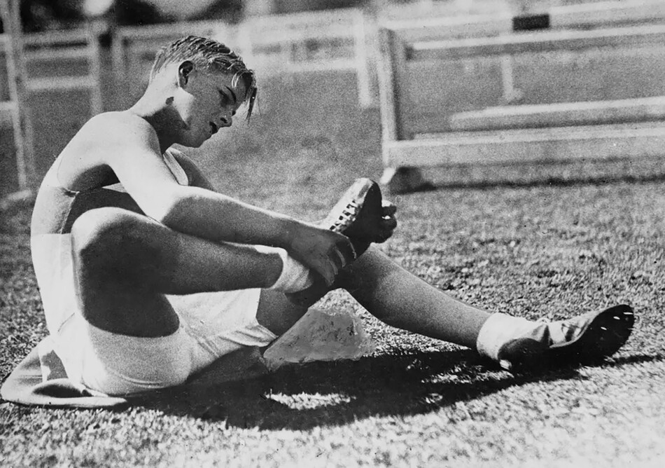 Принц Греции и Дании Филипп (позже Филип Маунтбэттен, а затем принц Филипп, герцог Эдинбургский) проверяет шипы своих кроссовок перед тем, как принять участие в межшкольном спортивном дне в Эдинбурге, Шотландия, в 1935 году