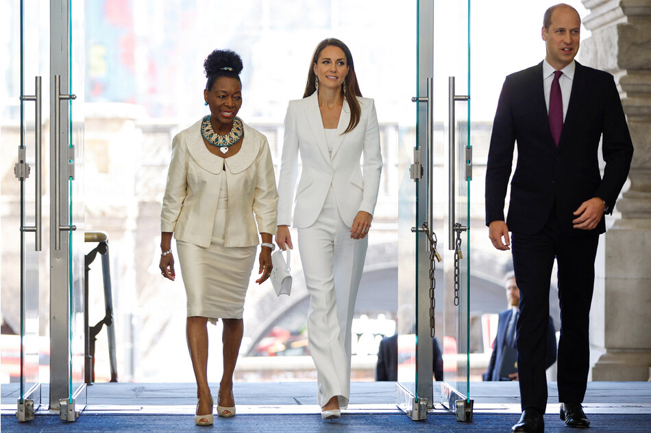 Принц Уильям, герцог Кембриджский и Кэтрин, герцогиня Кембриджская в сопровождении баронессы Флоэллы Бенджамин (слева) прибывают на открытие Национального памятника Виндраш на вокзале Ватерлоо в Лондоне 22 июня 2022 года