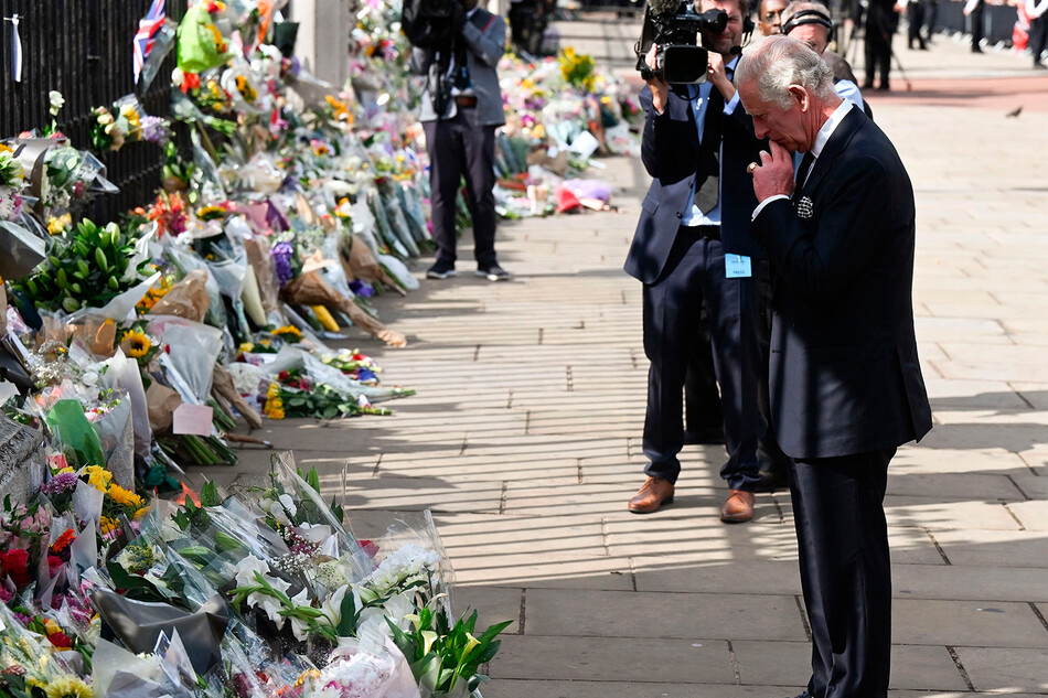 Король Карл III рассматривает цветы возложенные в честь покойной королевы Елизаветы II возле Букингемского дворца 9 сентября 2022 года в Лондоне, Великобритания