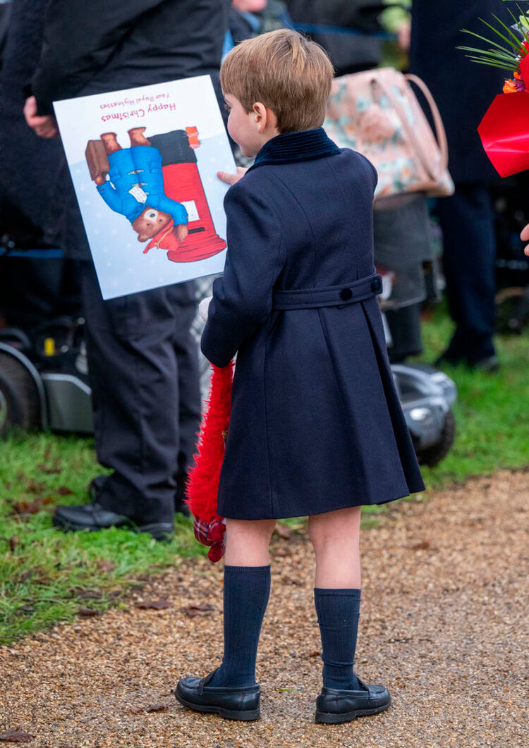 Принц Луи изучает подаренный ему рисунок во время посещения рождественской службы в Сандрингемской церкви 25 декабря 2022 года, Норфолк