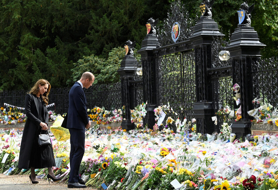 Уильям, принц Уэльский и Кэтрин, принцесса Уэльская рассматривают цветы возложенные поданными королевства в дань умершей королевы Елизаветы II у ворот поместья Сандрингем 15 сентября 2022 года в Сандрингеме, Англия